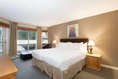 a bedroom with a large bed and a large window at Woodrun Lodge 211 | Ski-In Ski-Out Condo w/ Heated Pool, Hot Tub, Parking, & Gym in Whistler
