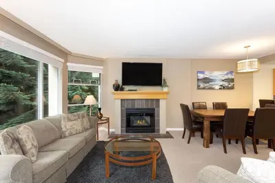 a living room with a couch and a table with a fireplace at Woodrun Lodge 514 | Ski-In Ski-Out Condo w/ Pool, Hot Tub, Free Parking, Wifi & Laundry in Whistler