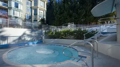a hot tub on a patio next to a building at Woodrun Lodge 514 | Ski-In Ski-Out Condo w/ Pool, Hot Tub, Free Parking, Wifi & Laundry in Whistler