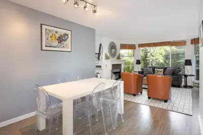 a kitchen and living room with a white table and chairs at Woodrun Lodge 107 | New Listing! Ski-in, Ski-Out, Heated Pool, Hot Tub & Parking in Whistler