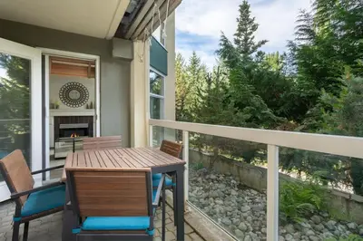 a porch with a wooden table and chairs on a balcony at Woodrun Lodge 107 | New Listing! Ski-in, Ski-Out, Heated Pool, Hot Tub & Parking in Whistler