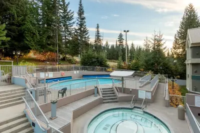 a pool on a building with stairs and a swimming pool at Woodrun Lodge 107 | New Listing! Ski-in, Ski-Out, Heated Pool, Hot Tub & Parking in Whistler