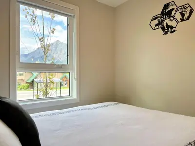 a bedroom with a bed and a window at Brand New 2BR Condo with Outdoor Swimming Pool and Hot Tub in Canmore
