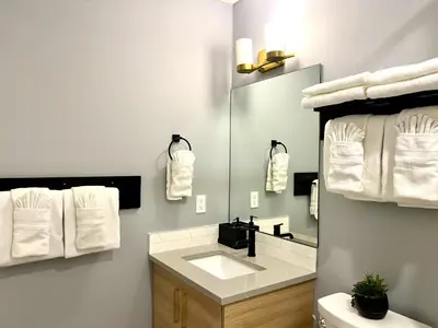 a bathroom with a sink and a mirror and towels at Brand New 2BR Condo with Outdoor Swimming Pool and Hot Tub in Canmore
