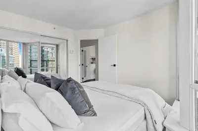 a white bedroom with a large white bed with pillows at Downtown Luxury 1BR Coal Harbour in Vancouver
