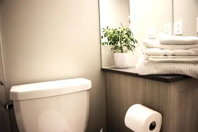 a bathroom with a toilet and a mirror and towels at Like cozy place in Calgary