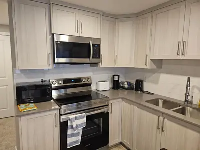 a kitchen with stainless steel appliances and white cabinets at Like cozy place in Calgary