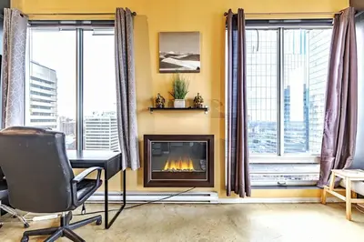 a living room with a fireplace and windows at Industrial-Style Cityscape 1 Bedroom Loft in Edmonton