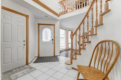 a hallway with stairs and a door with a chair at Coral Springs Lakefront Retreat in Calgary