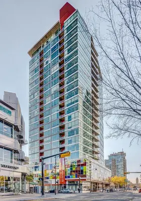 a tall building with glass windows on a city street at Cozy 2BR Condo with King Bed and City Views in Calgary