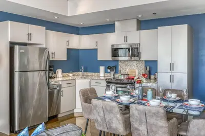 a kitchen with a table with chairs and a refrigerator at Cozy 2BR Condo with King Bed and City Views in Calgary