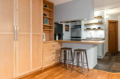 a kitchen with wooden cabinets and a counter with stools at Casa Creekside - Walk to Gondola, Shops, lakes! in Whistler