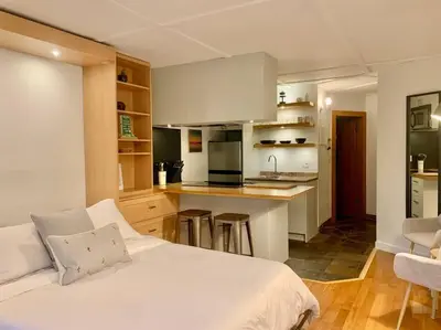 a bedroom with a white bed and a kitchen at Casa Creekside - Walk to Gondola, Shops, lakes! in Whistler