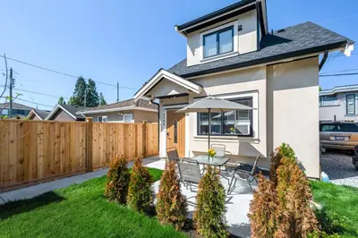 a backyard with a fence and a table with an umbrella at Three bedrooms new laneway house near public transit & FIFA training site in Vancouver