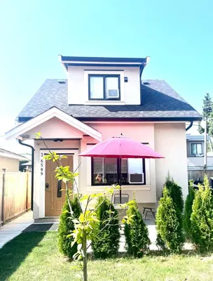 a pink house with a red umbrella in the front yard at Three bedrooms new laneway house near public transit & FIFA training site in Vancouver