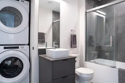 a bathroom with a washing machine and a sink at Snowed Inn - Stunning 3 Bedroom Condo in Revelstoke