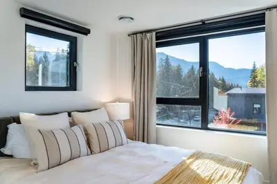 a bedroom with a bed and a large window at Snowed Inn - Stunning 3 Bedroom Condo in Revelstoke