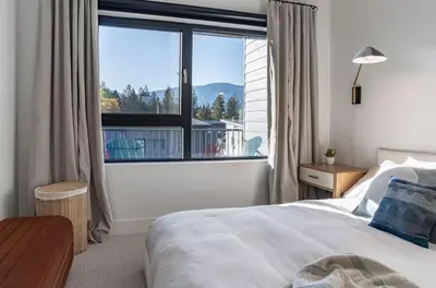 a bedroom with a bed and a large window at Snowed Inn - Stunning 3 Bedroom Condo in Revelstoke
