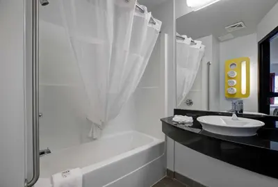a bathroom with a tub and a sink and a bath tubermottermott at Motel 6 Airdrie in Airdrie