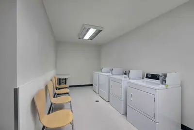 a row of white washers and dryers in a room at Motel 6 Airdrie in Airdrie