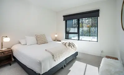 a white bedroom with a bed and a window at Mountainview Escape by Revelstoke Vacations in Revelstoke