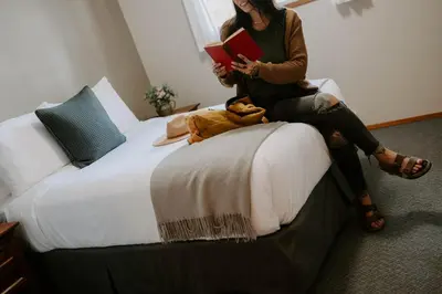 a woman sitting on a bed reading a book at Page's Resort & Marina in Gabriola