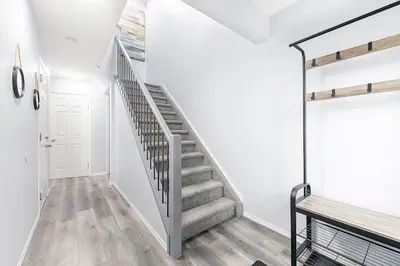 a staircase in a house with white walls and wooden floors at Large Townhome Near Anthony Henday in Ellerslie with Driveway & Visitor Parking, King Bed, 4 Queen Beds, Fully Equipped Kitchen & More! in Edmonton