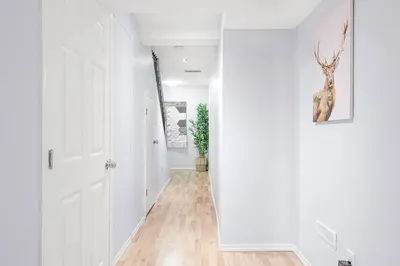 a hallway with white walls and a white door at Large Townhome Near Anthony Henday in Ellerslie with Driveway & Visitor Parking, King Bed, 4 Queen Beds, Fully Equipped Kitchen & More! in Edmonton