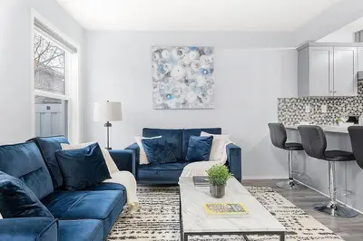 a living room with a blue couch and a table at Large Townhome Near Anthony Henday in Ellerslie with Driveway & Visitor Parking, King Bed, 4 Queen Beds, Fully Equipped Kitchen & More! in Edmonton