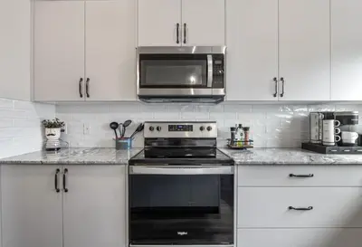 a white kitchen with a stove and a microwave at Extra Large House with AC, Banff Access, Sleep 12, BBQ, 4 Bedrooms & 2 Sleeper Sofa Beds in Airdrie