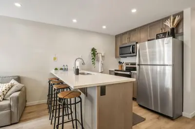 a kitchen with a refrigerator and some bar stools at Private Town Home with Free Banff Access, Netflix, King Bed, Fully Equipped Kitchen, Sleeps 4 in Calgary