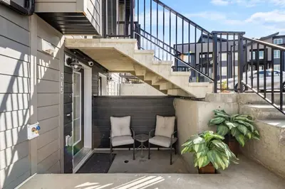 a balcony with two chairs and a table and stairs at Private Town Home with Free Banff Access, Netflix, King Bed, Fully Equipped Kitchen, Sleeps 4 in Calgary