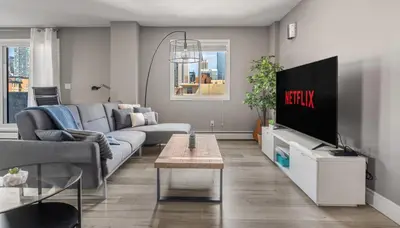 a living room with a couch and a tv at Downtown Apartment with Underground Parking, Netflix, Fully Equipped Kitchen, Walk to 17th Ave, Sleeps 4, Perfect for Foodies and Tourists in Calgary