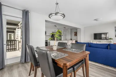 a dining room with a table and a blue couch at 4 Bedroom Town Home with Garage Parking, Fast WiFi, Smart TV with Netflix, Fully Equipped Kitchen, Sleeps 10, Ideal for Families in Airdrie