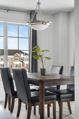 a dining room table with black chairs and a potted plant at 4 Bedroom Town Home with Garage Parking, Fast WiFi, Smart TV with Netflix, Fully Equipped Kitchen, Sleeps 10, Ideal for Families in Airdrie