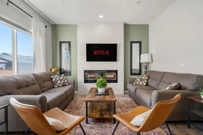 a living room with a couch and a fireplace at Top Rated Luxury House with Central AC, Double Garage Parking, 2 Kitchens, 5 Bedrooms & More! in Balzac