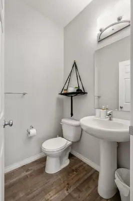a white bathroom with a toilet and a sink at Top Rated Luxury House with Central AC, Double Garage Parking, 2 Kitchens, 5 Bedrooms & More! in Balzac