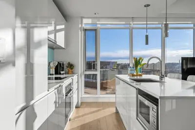 a kitchen with white counters and a large window at Luxury Apartment on the 9th Floor near Stampede, Complimentary Wine, 2 Car UG Parking in Calgary