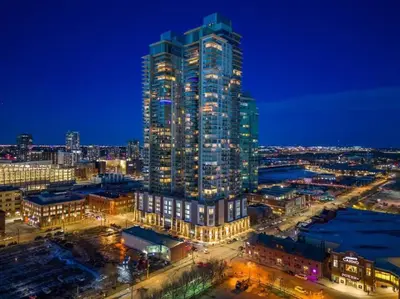 a tall building with lights on in a city at night at Luxury Apartment on the 9th Floor near Stampede, Complimentary Wine, 2 Car UG Parking in Calgary