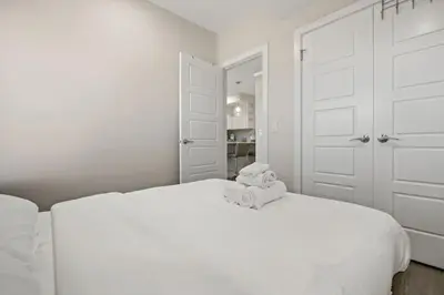 a white bedroom with a white bed with two stuffed animals on it at Private Suite with Queen Bed, Queen Sofa Bed, Netflix, Patio, Sleeps 4 in Calgary