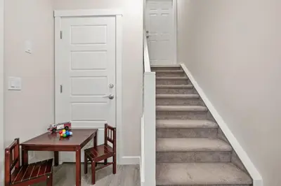 a hallway with a staircase with a table and a door at Private Suite with Queen Bed, Queen Sofa Bed, Netflix, Patio, Sleeps 4 in Calgary