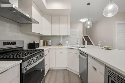 a white kitchen with a stove and a sink at Private Suite with Queen Bed, Queen Sofa Bed, Netflix, Patio, Sleeps 4 in Calgary