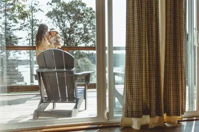 a woman holding a child standing on a porch looking out the window at Page's Inn on Silva Bay in Gabriola