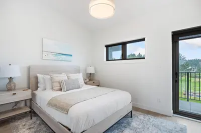 a white bedroom with a bed and a window at Coastal Haven at THE BEACH HOUSE in Campbell River