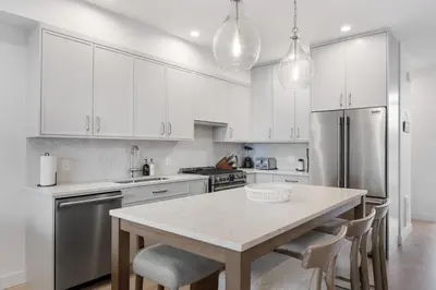 a kitchen with white cabinets and a table with chairs at Coastal Haven at THE BEACH HOUSE in Campbell River