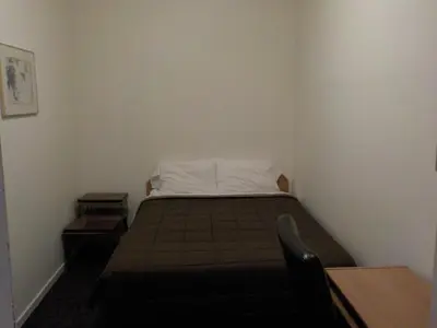 a small bedroom with a bed and a table at Vernon Hostel in Vernon