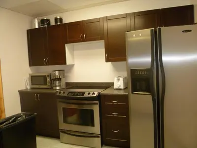 a kitchen with wooden cabinets and a stainless steel refrigerator at Vernon Hostel in Vernon