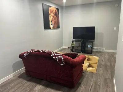 a living room with a red couch and a television at Cute Highland Park Upper B Unit in Calgary