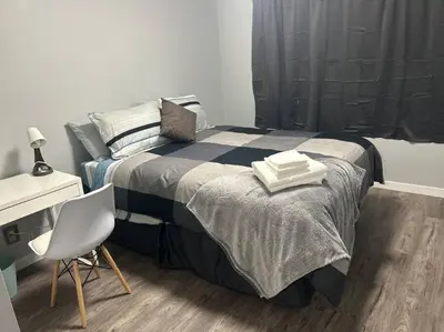 a bedroom with a bed with a desk and a chair at Cute Highland Park Upper B Unit in Calgary