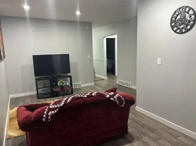 a living room with a red couch and a flat screen tv at Cute Highland Park Upper B Unit in Calgary